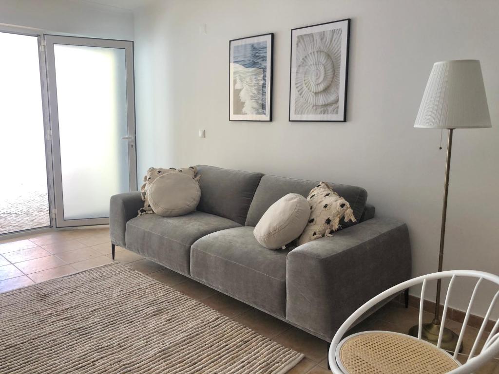 una sala de estar con un sofá gris con almohadas. en Apartamento Espaçoso Sesimbra en Sesimbra