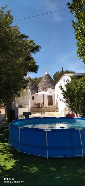 a blue swimming pool in front of a house at Trulli di nonno Ciccio in Cisternino