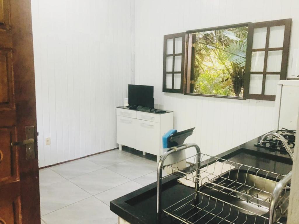 a kitchen with a sink and a desk with a computer at Chalé Mar e Montanha in Trindade