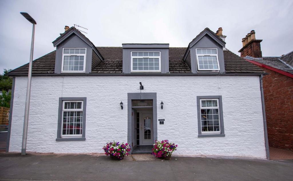 a white house with flowers in front of it at Braeside Guest House, Loch Lomond in Drymen