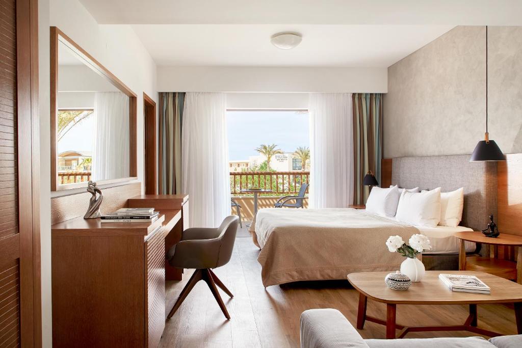 a hotel room with a bed and a balcony at Minoa Palace Resort in Platanias