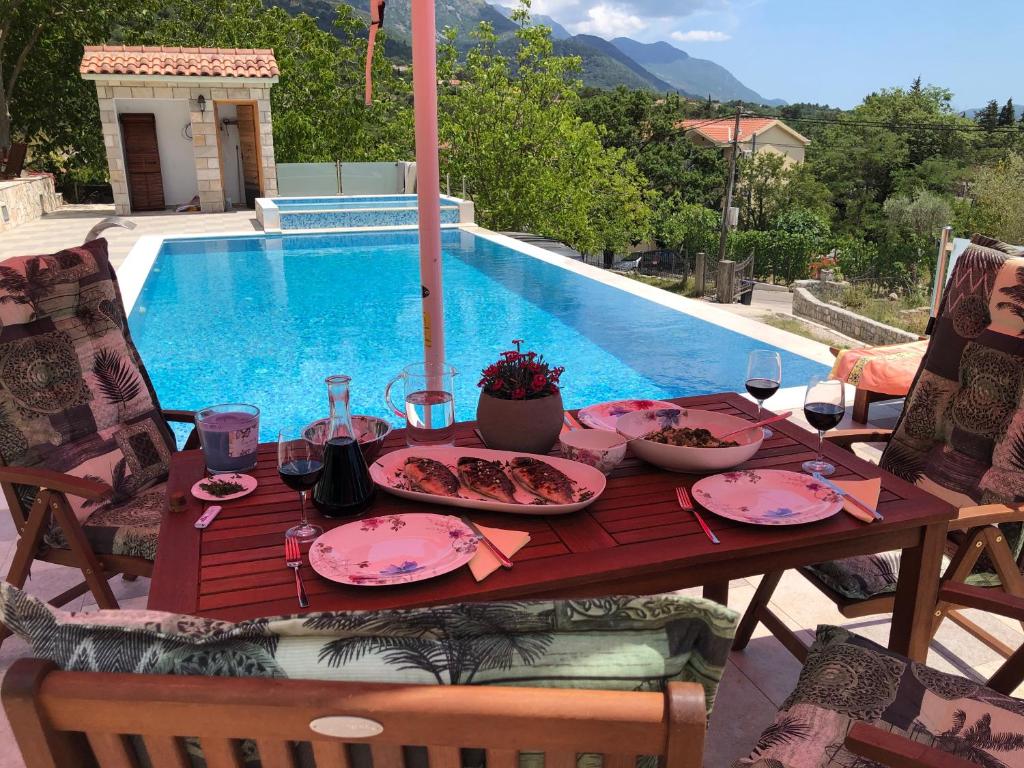 a table with plates of food next to a swimming pool at Villa Katarina in Tivat