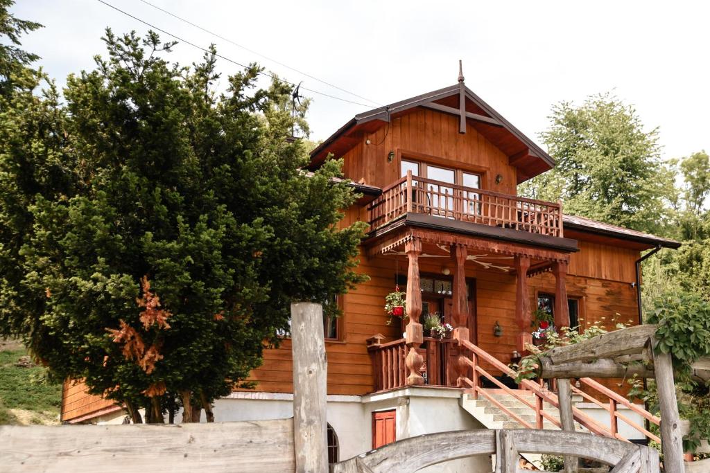 een houten huis met een veranda en een balkon bij Cisówka Pokoje Gościnne in Piwniczna