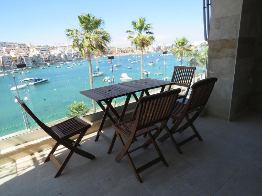 una mesa y sillas en un balcón con vistas al agua en Aquamarine Sea Front Apartments - Second Floor, en Marsaskala