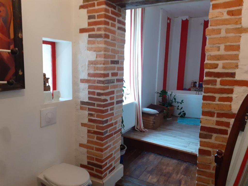 a bathroom with a brick wall and a toilet at Ancien Presbytère in La Chapelle-dʼAngillon