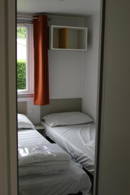 two beds in a room with a window at Les mobiles Homes de la Palmyre in Les Mathes
