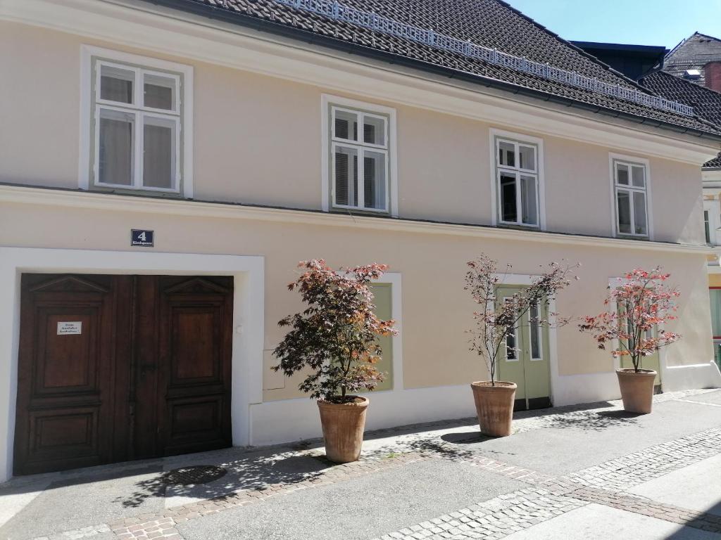 uma casa branca com duas portas e dois vasos de plantas em Gästewohnung Helena em Völkermarkt
