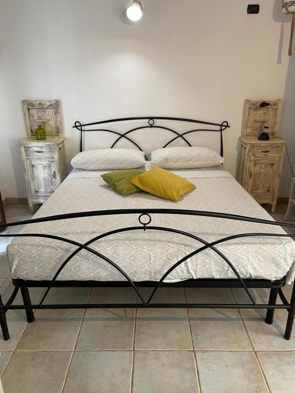 a bed with a black metal frame and yellow pillows at Entula 'E Mari Bed&Brakfast in Tortolì