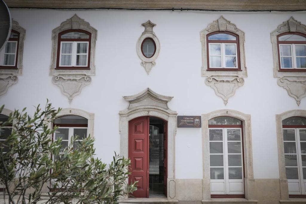 biały budynek z czerwonymi drzwiami i oknami w obiekcie Casa Das Condessinhas w mieście Lousã
