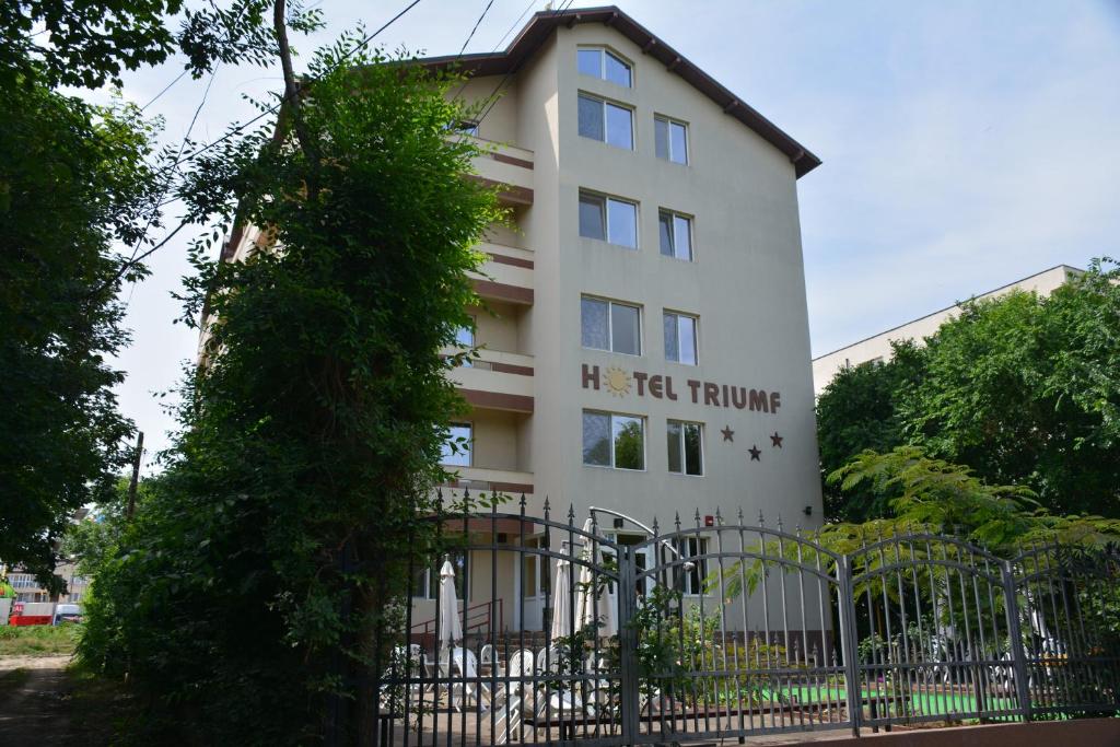 a white building with a fence in front of it at TRIUMF in Costinesti