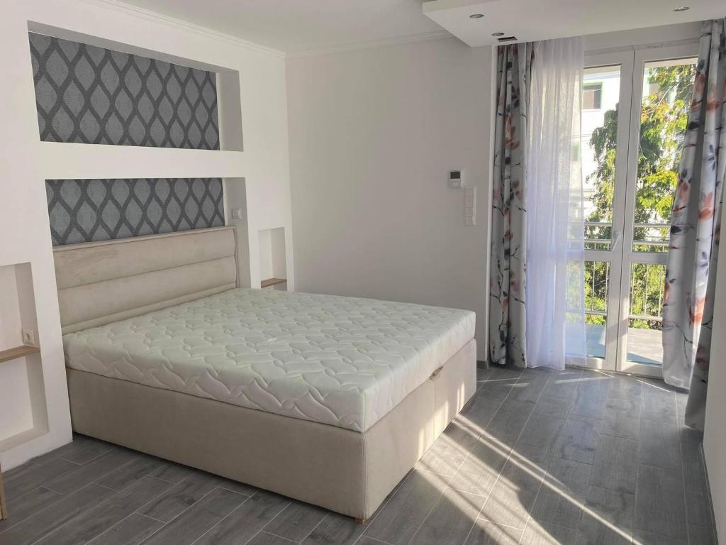 a white bedroom with a bed and a window at Szőlőlugas Vendégház in Balatonfüred