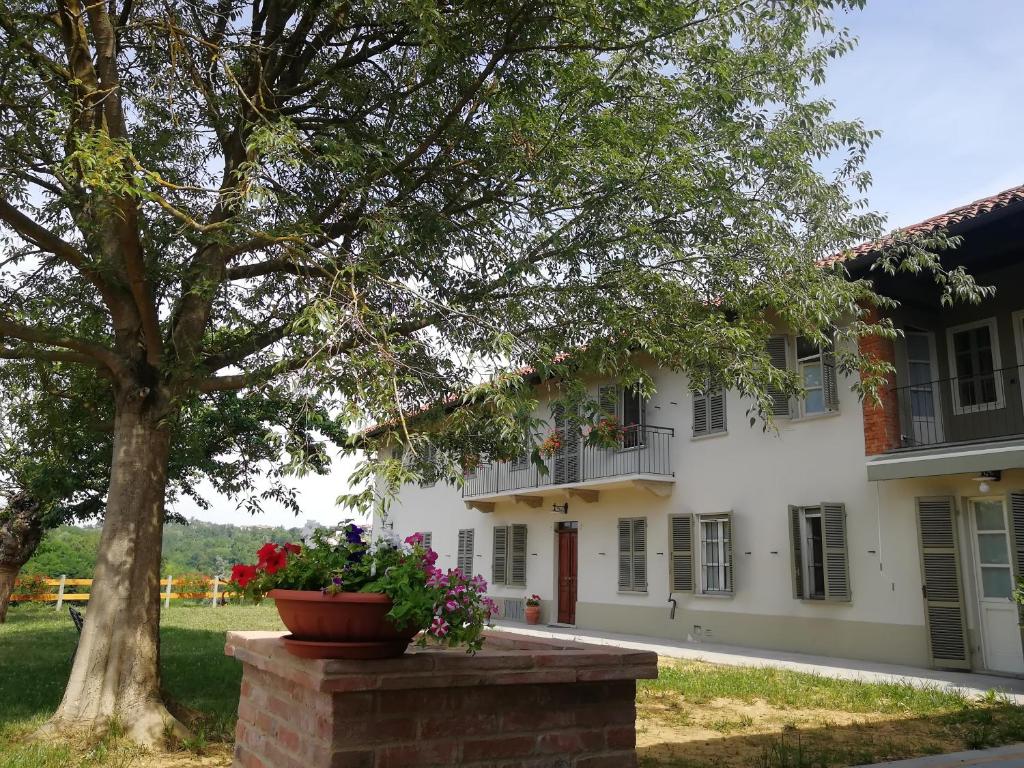 un grande edificio bianco con un albero e fiori di Agriturismo IL FRA' a Tigliole