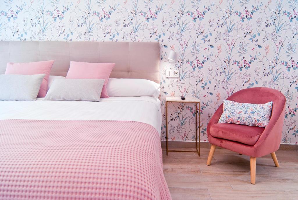1 dormitorio con 1 cama y 1 silla rosa en Destino Guadalest - Apartments by Cases Noves en Guadalest