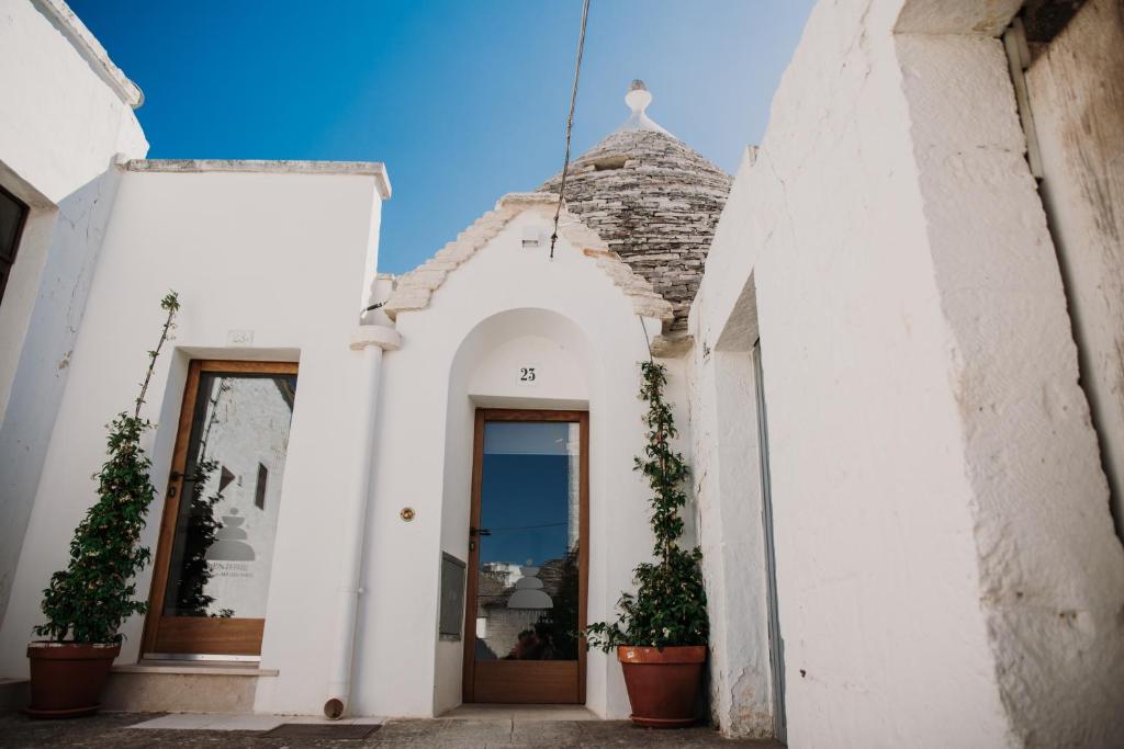 a white building with potted plants in front of it at VENTITRÈ- House of Apulia Mea in Alberobello