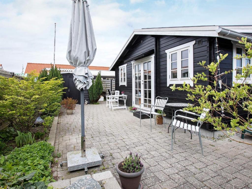 um pátio com um guarda-chuva em frente a uma casa preta em Holiday home Karrebæksminde XLIV em Karrebæksminde