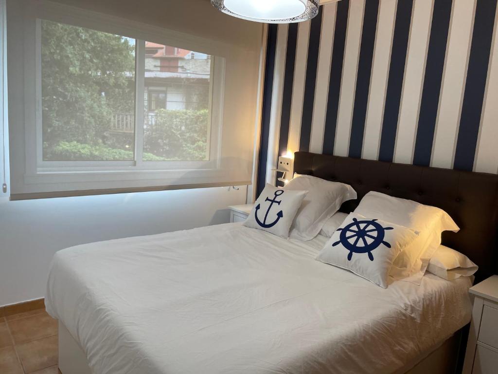 łóżko z dwiema poduszkami i oknem w obiekcie Portosín -Suites w mieście Portosin