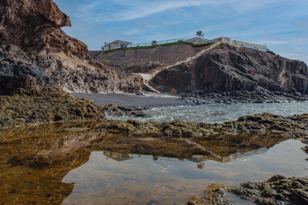 a reflection of the water on a rocky beach at Etti Paradise - Suite La Luna in Pájara