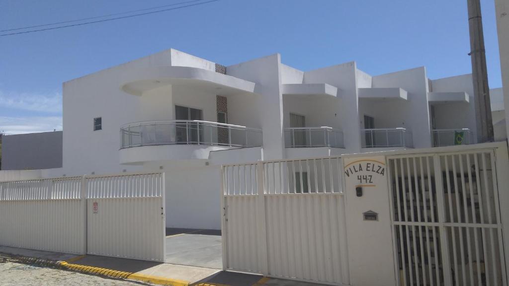 a white building with a gate and a fence at Casa-2 Condomínio Elza em Arraial do Cabo in Arraial do Cabo
