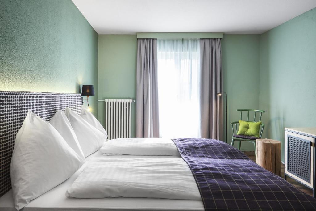 a bedroom with a bed with white sheets and a window at Hotel Bären in St. Moritz