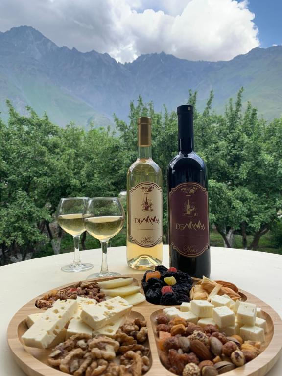 uma mesa com um prato de queijo e dois copos de vinho em Guest House Demma em Kazbegi