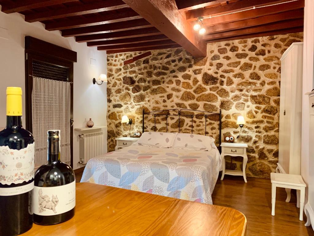 Casa tio Basilio في بانيوس دي مونتيمايور: غرفة نوم مع سرير وزجاجتين من النبيذ