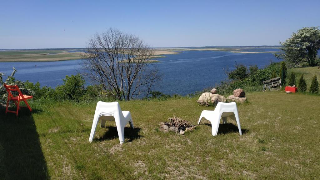 two people sitting in a field with two white chairs at Dom na Klifie in Międzyzdroje