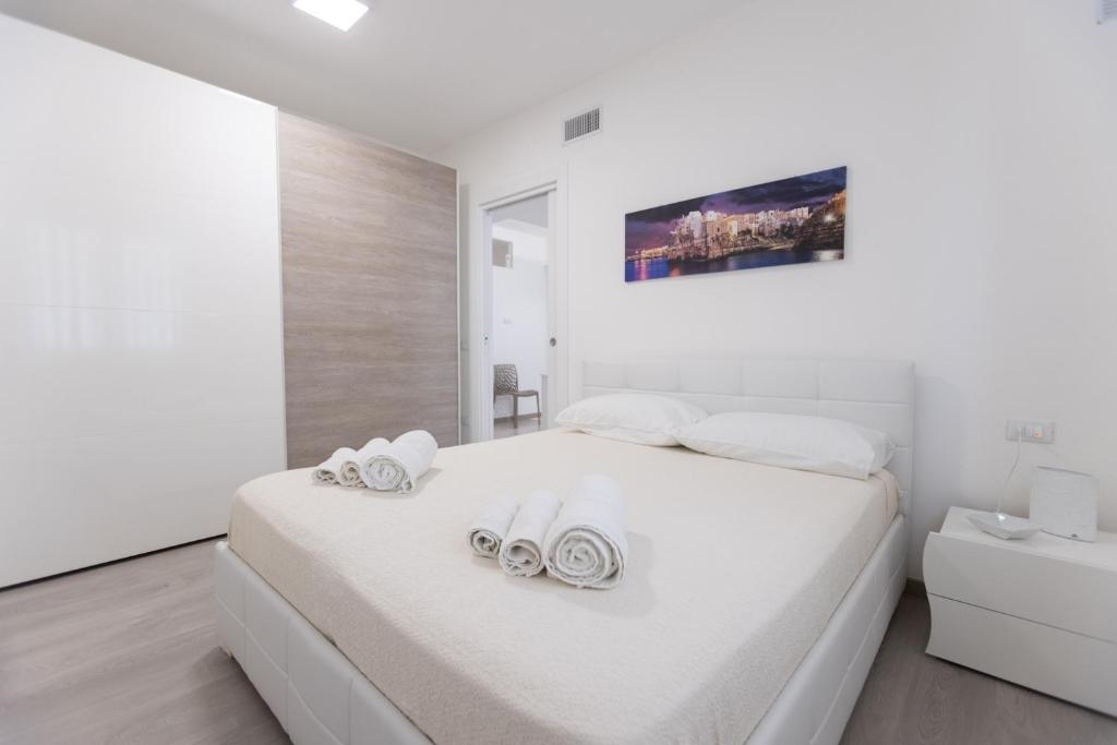 ein weißes Schlafzimmer mit einem großen weißen Bett mit Handtüchern darauf in der Unterkunft B&B Il più bello dei mari in Polignano a Mare