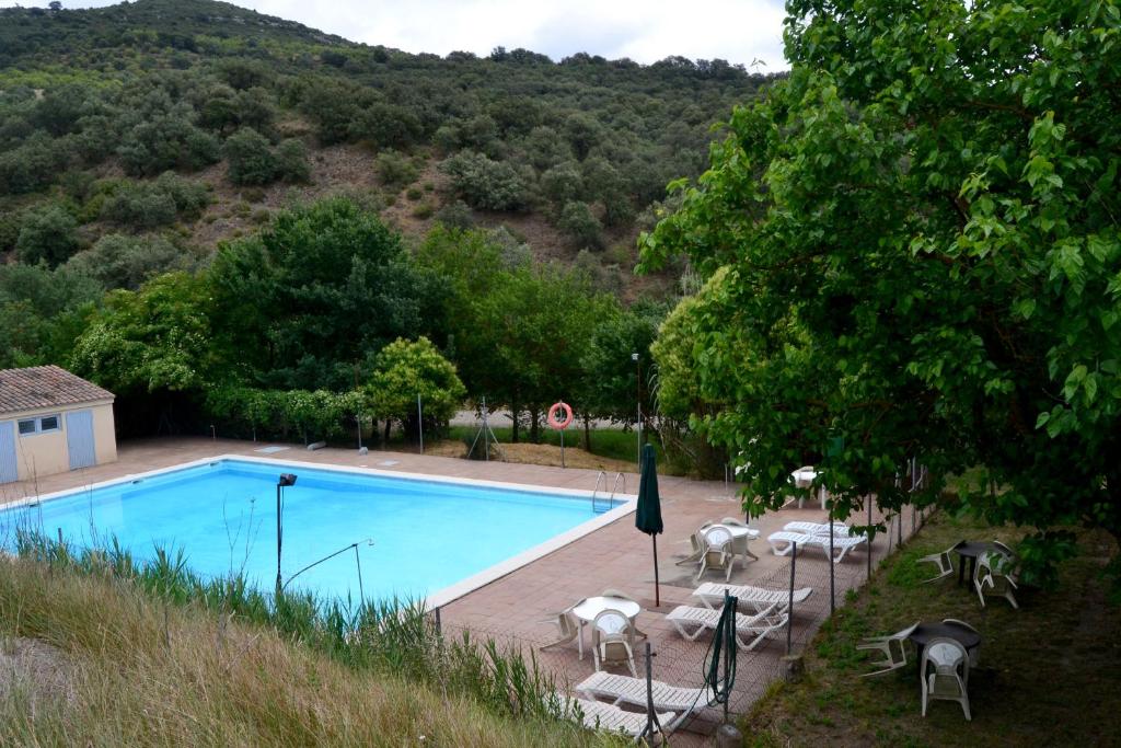 a swimming pool with tables and chairs next to a mountain at Masia Molí de Tartareu in Tartareu