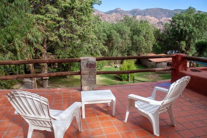 three white chairs and a table on a patio at Cabañas Malka in Tilcara