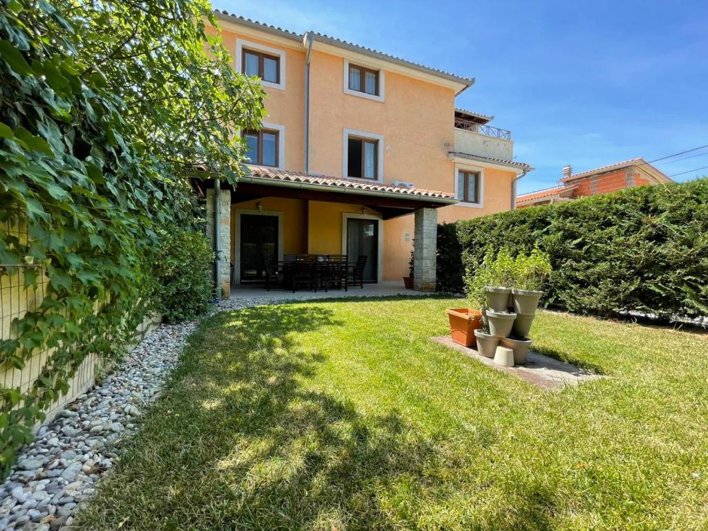 a house with a yard with grass and a fence at Apartments Ladonja in Medulin