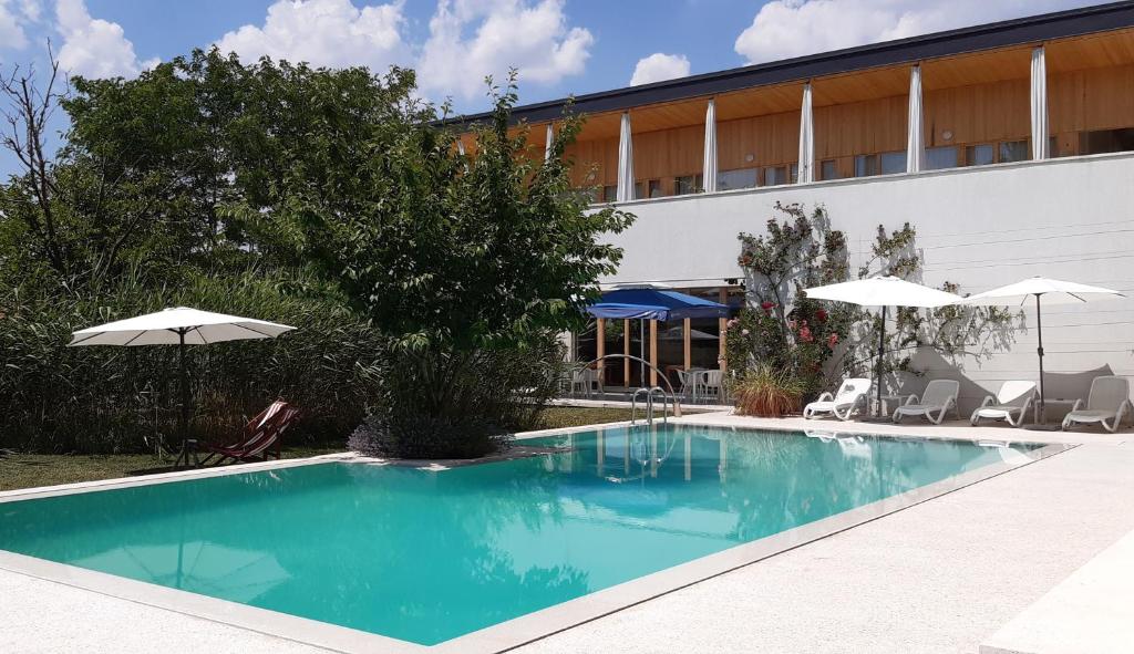 einen Pool mit Stühlen und Sonnenschirmen neben einem Gebäude in der Unterkunft Hotel Gracanica in Pristina