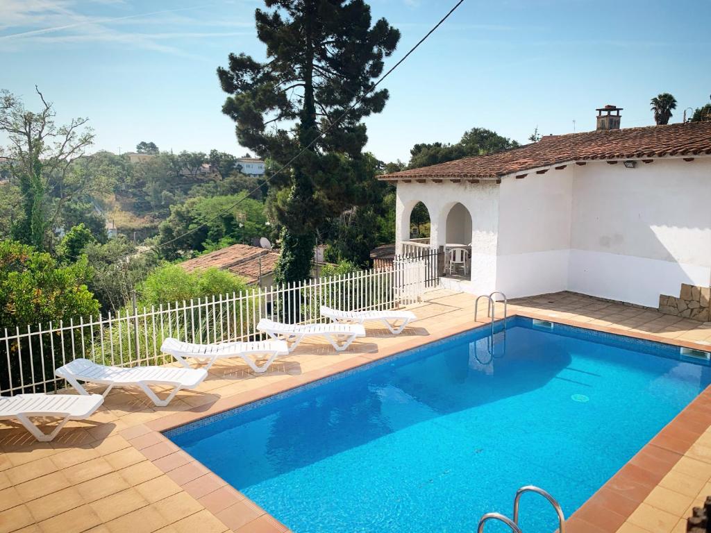 een zwembad met stoelen en een huis bij Villa Mas Blau in Lloret de Mar