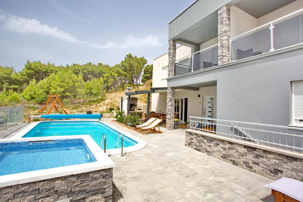 eine Außenansicht eines Hauses mit Pool in der Unterkunft Villa Sara with Sea View and Private Heated Pool in Omiš