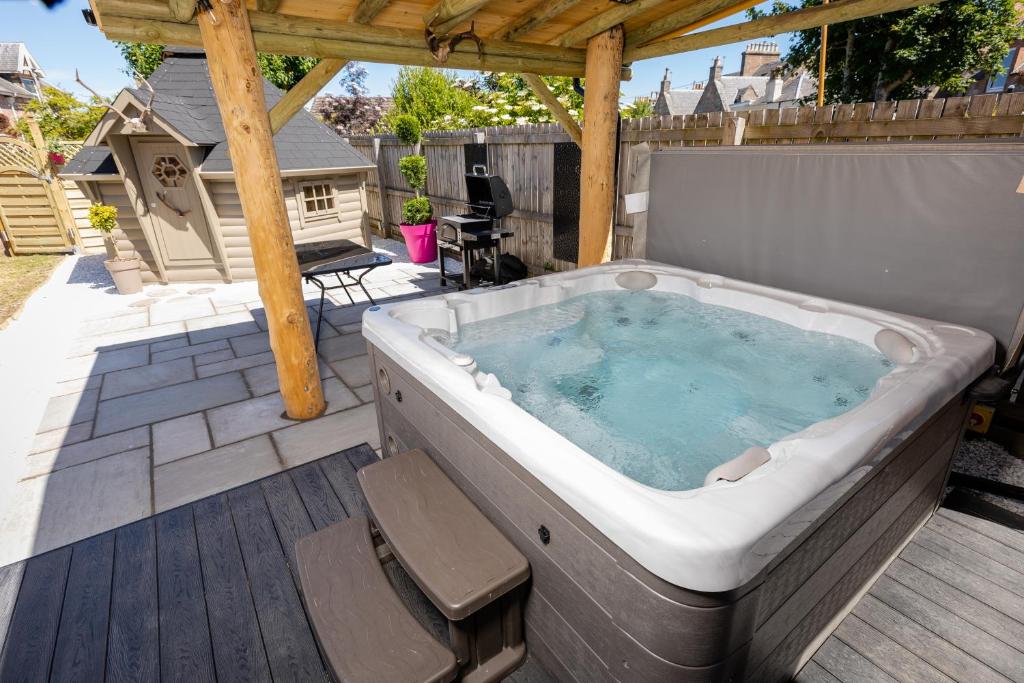 a hot tub on a deck with a pergola at Aye Stay Home, city centre in Inverness