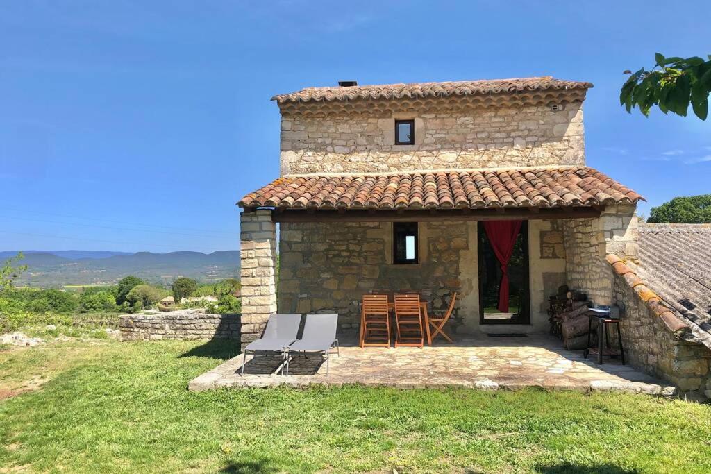 a stone house with a patio and a table and chairs at Gîte du Mas in Saint-Privat-de-Champclos