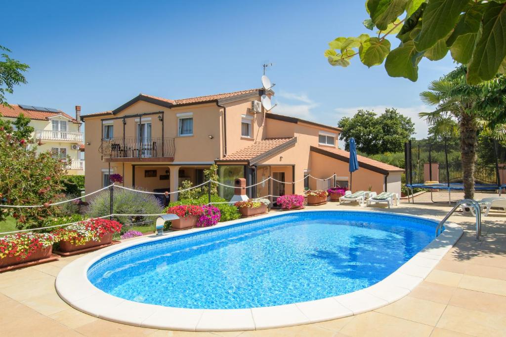 a swimming pool in front of a house at Apartments Flora in Rošini