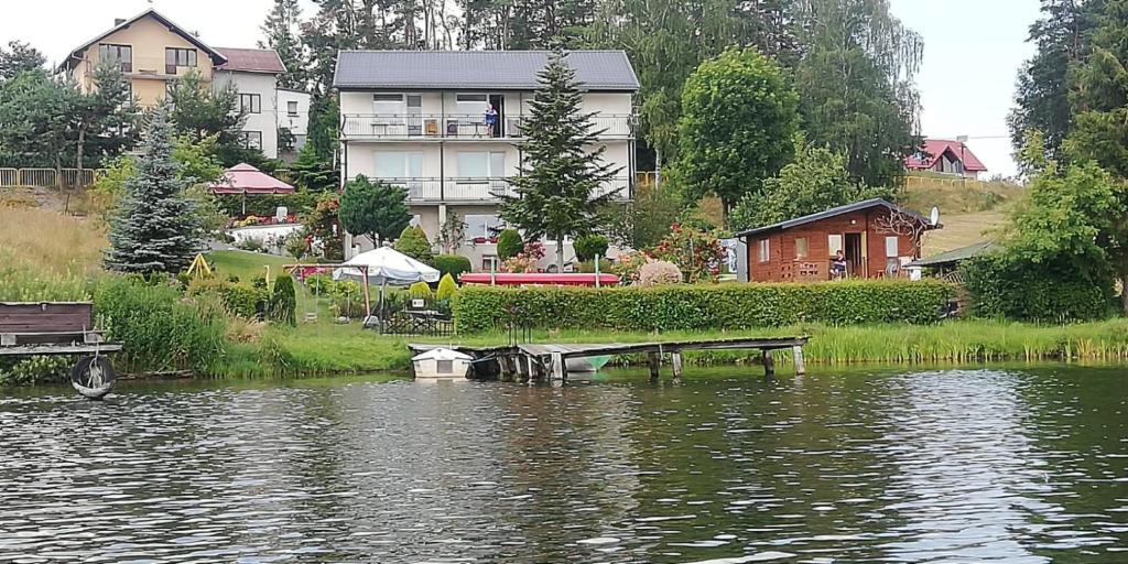 a house sitting next to a body of water at Lemanka in Gowidlino