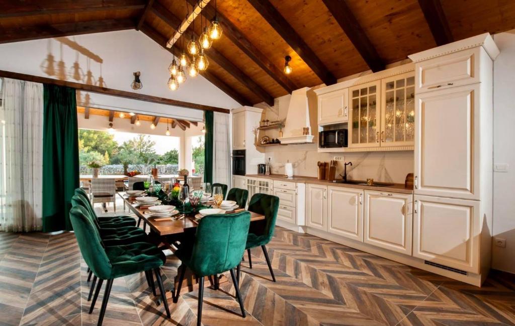 a kitchen and dining room with a table and green chairs at Luxury Villa Nature with heated private pool, sauna & fire pit, a short walk to the beach in Milna