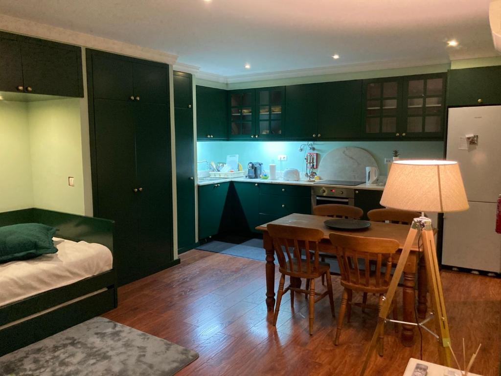 a kitchen with green cabinets and a table and a bed at Studio by Casa da Quinta in Funchal