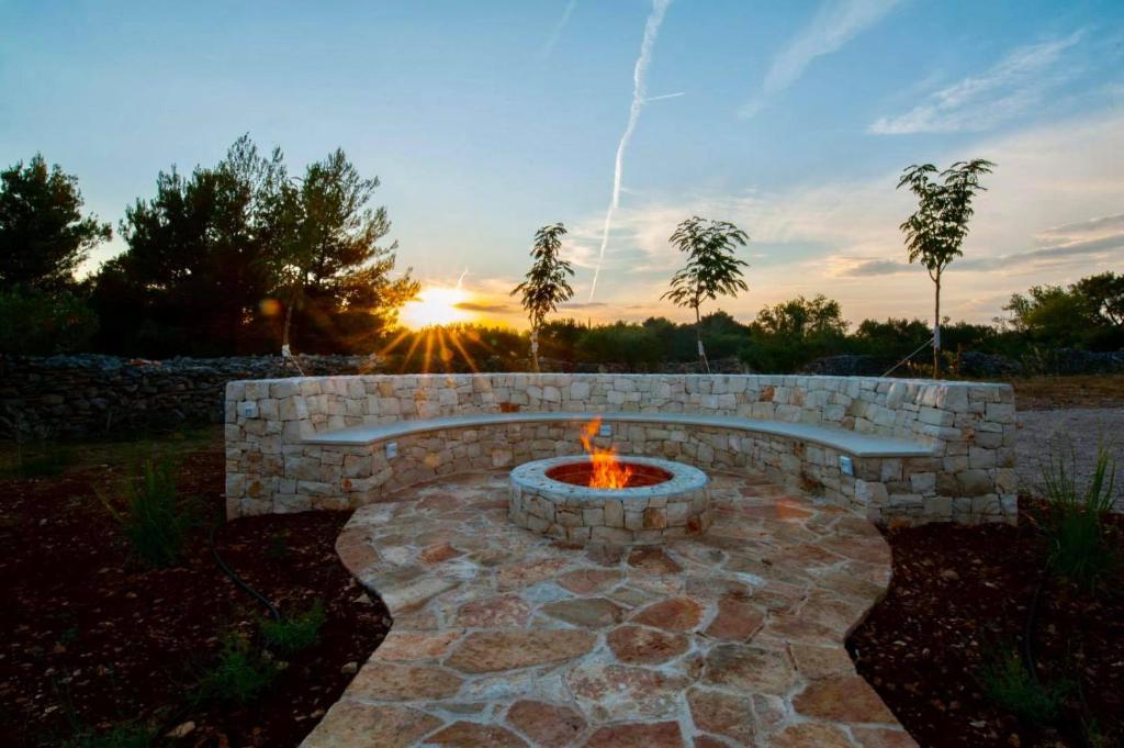 a fire pit in a yard with the sunset in the background at Luxury Villa Nature with heated private pool, sauna & fire pit, a short walk to the beach in Milna
