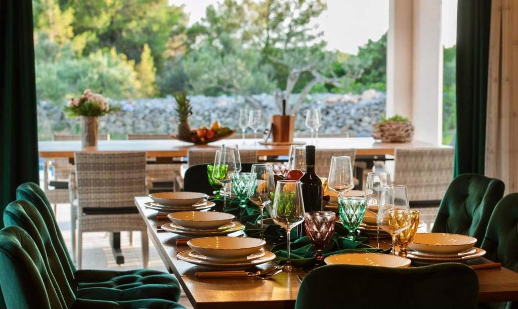 a wooden table with glasses and plates on top of it at Luxury Villa Nature with heated private pool, sauna & fire pit, a short walk to the beach in Milna