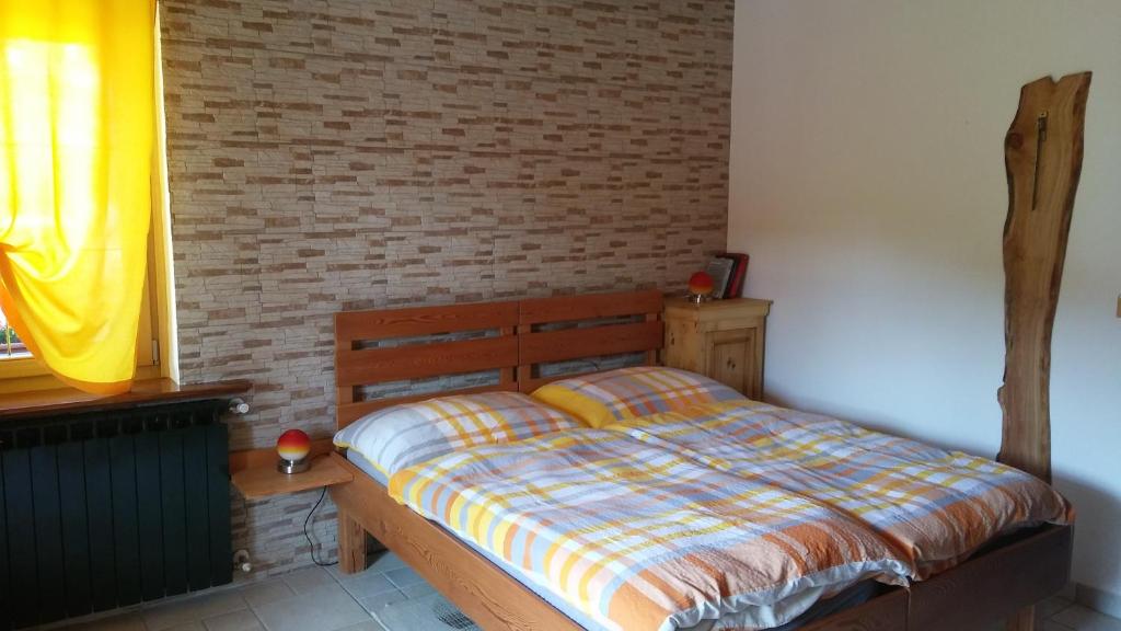1 dormitorio con cama y pared de ladrillo en Huatscher, en Camporosso in Valcanale