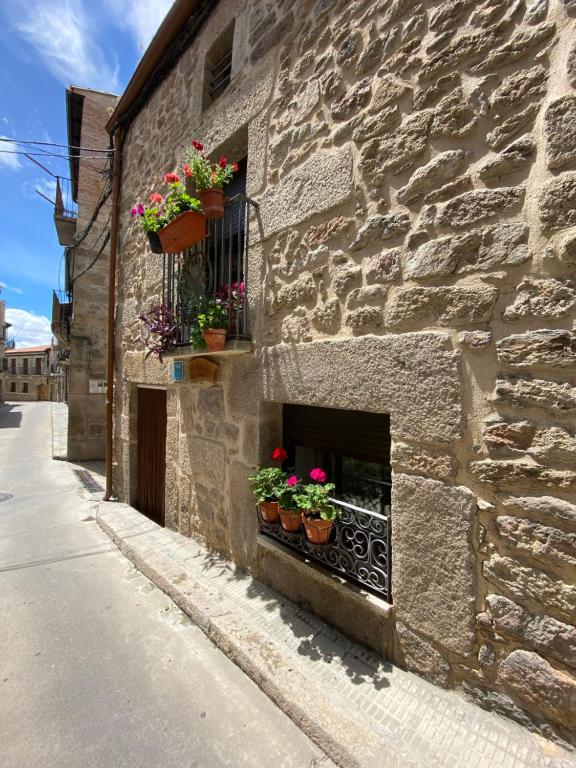 a stone building with potted plants on a window at Casa del Carabinero in Fermoselle