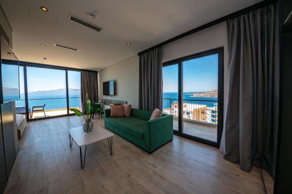 a living room with a green couch and large windows at Apart-Hotel Lili2 in Sarandë
