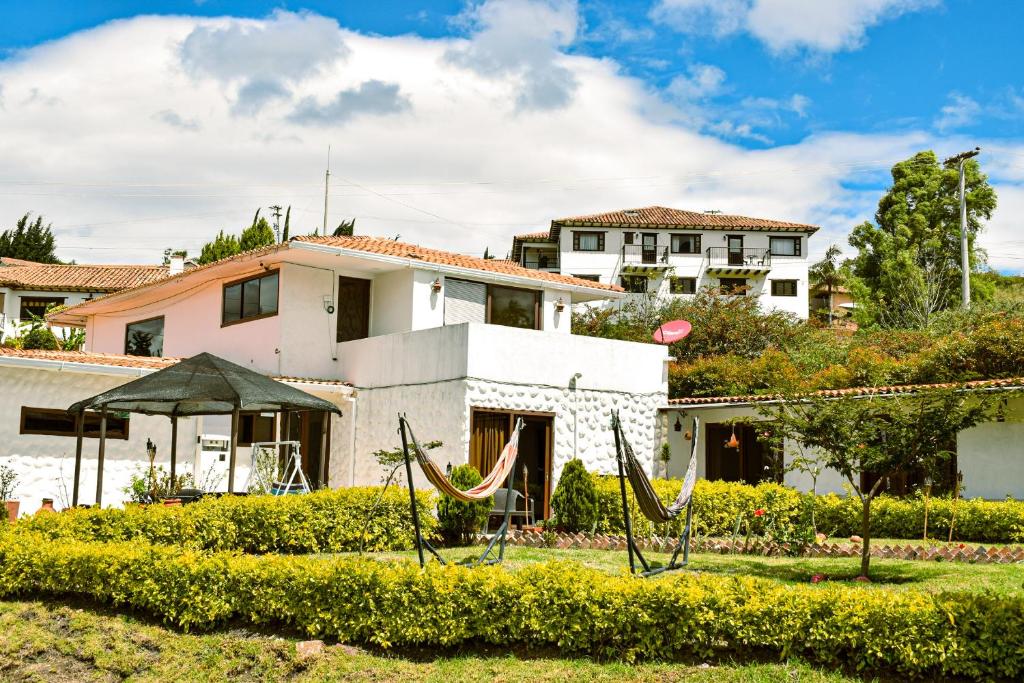 a house with hammocks in front of a yard at Posada Tierra Viva in Villa de Leyva