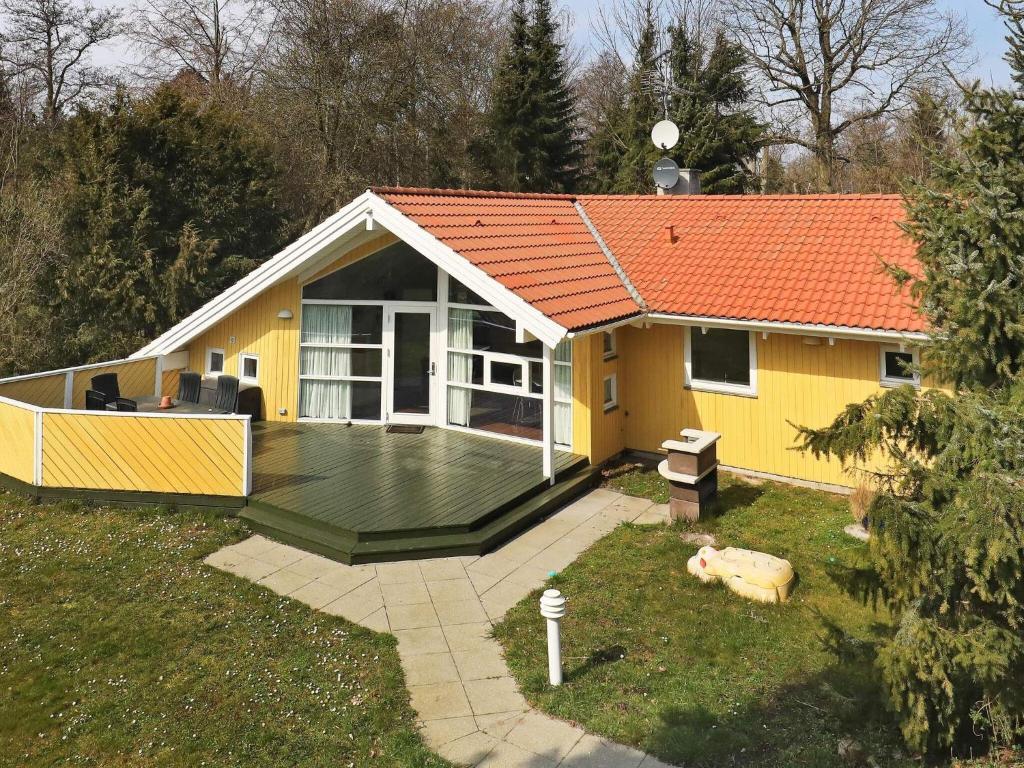 ein kleines gelbes Haus mit einer großen Terrasse in der Unterkunft 11 person holiday home in Str by in Strøby