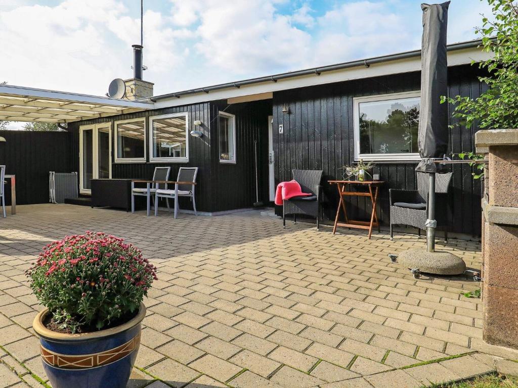 un patio con sillas, una mesa y una casa en Three-Bedroom Holiday home in Sæby 4, en Nordost