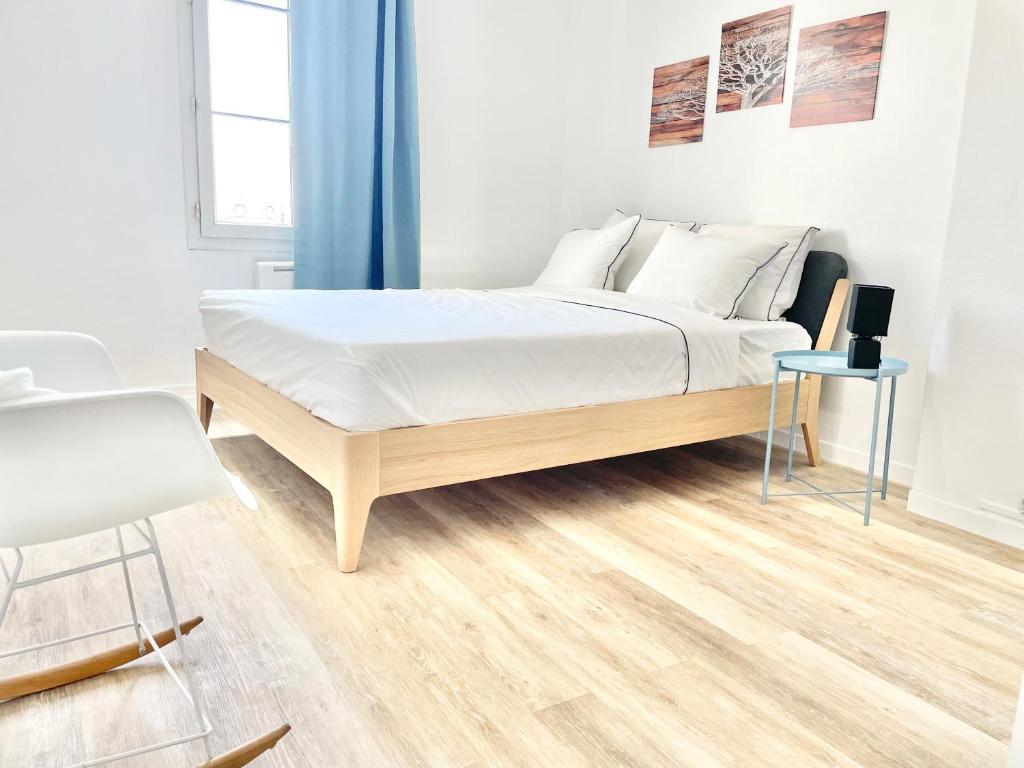 a bedroom with a bed with white sheets and a blue curtain at Arina & Julien Dieppe in Dieppe