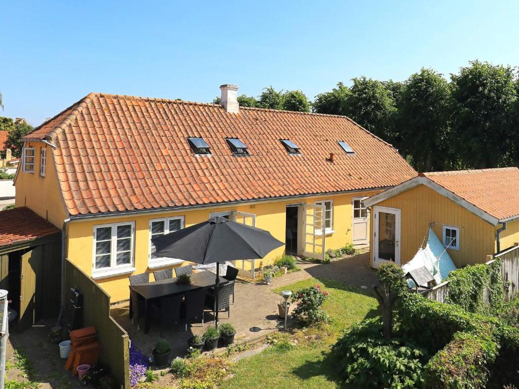 een geel huis met een tafel en een paraplu bij 11 person holiday home in r sk bing in Ærøskøbing