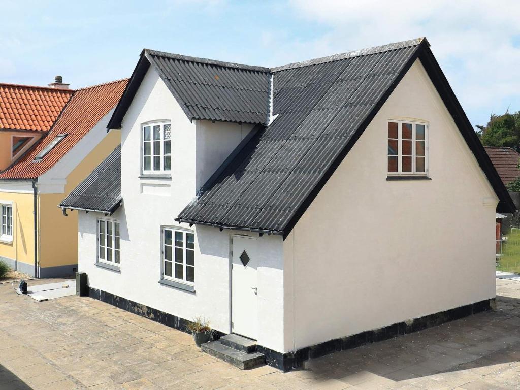 uma casa branca com um telhado preto em 6 person holiday home in L kken em Løkken